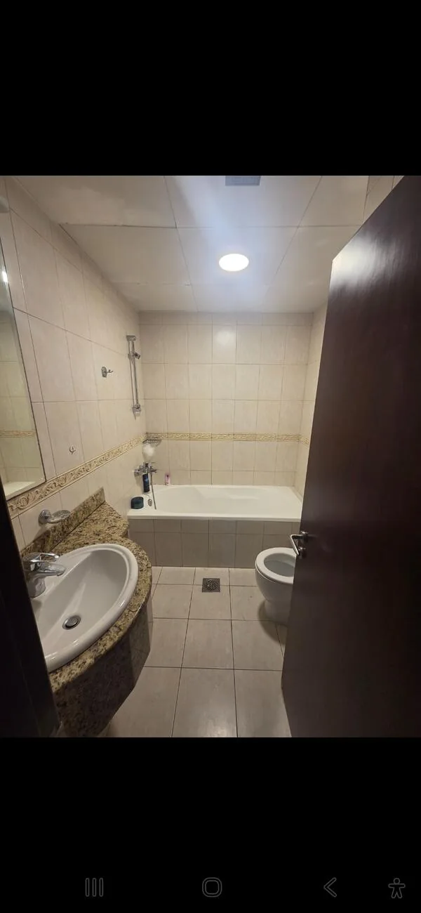 Bathroom before — dated beige tiling with bathtub