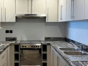 Kitchen after — cabinets refreshed with durable vinyl wrap and new flooring